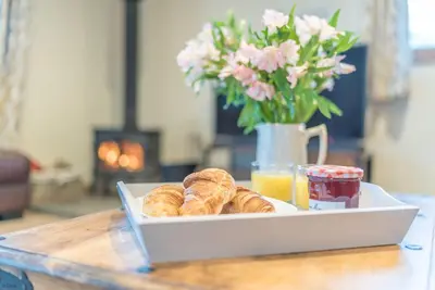 a tray of pastries and orange juice and a vase with flowers at Maes-Artro-Lodge in Llanbedr