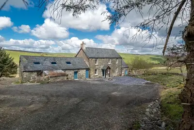 an old stone house on the side of a road at Erw-Dinmael in Corwen