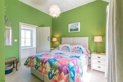 a bedroom with a colorful bed and green walls at Erw-Dinmael in Corwen