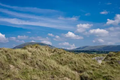a view of a grassy hill with mountains in the background at Ysgubor-Bennar in Dyffryn
