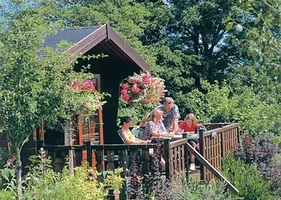 a group of people sitting on a porch of a house at Belan Bach Lodges in Towyn