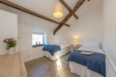 two beds in a room with wooden beams at Bwthyn-Bennar in Dyffryn