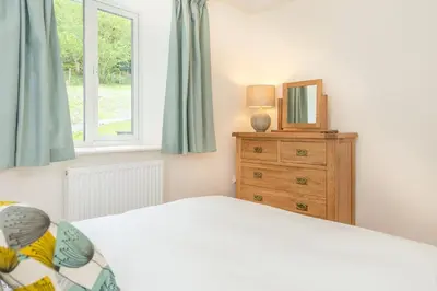a bedroom with a bed and a dresser with a mirror at Maes-Y-Coed in Dolgellau