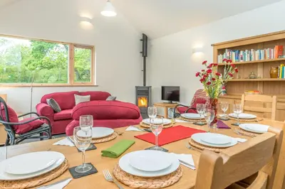 a dining room with a table with plates and wine glasses at Maes-Y-Coed in Dolgellau