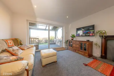 a living room with a couch and a flat screen tv at Allt-Goch in Llanbedr