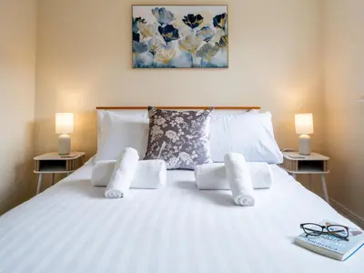 a white bed with two lamps and a book on it at Pass the Keys 3 Bedroom home local to Ludlow town centre in Ludlow