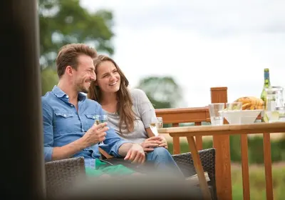a man and woman sitting at a table with a glass at Wigmore Lakes Lodges in Westbury