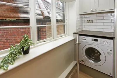 a kitchen with a washing machine and a window at St John's Hill Apartments in Shrewsbury