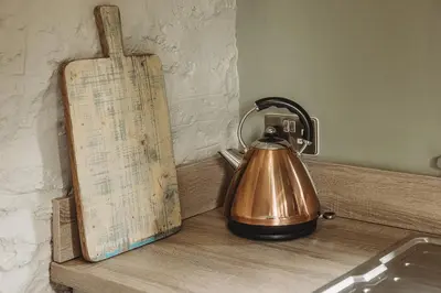 a tea kettle sitting on a counter next to a sign at Ty Bach in Llanwrtyd Wells