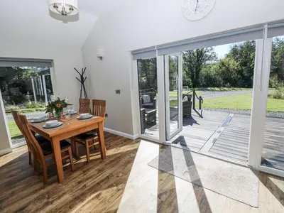 a dining room with a table and a large sliding glass door at Dwrgi in Llanybydder