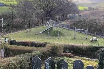 a cemetery with a park with a slide in the grass at Calm country cottage in Elerch