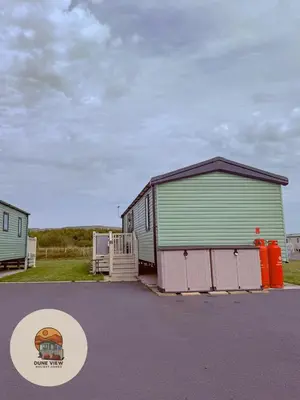 a large green and white building with a gate at Dune View Caravan in Ynys-lâs Station