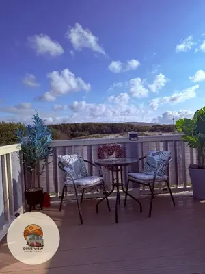 a patio with a table and chairs on a deck at Dune View Caravan in Ynys-lâs Station