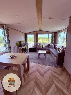 a living room with a couch and a table at Dune View Caravan in Ynys-lâs Station