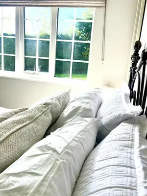 a bed with white pillows in a room with windows at Ty Newydd in Llangyniew