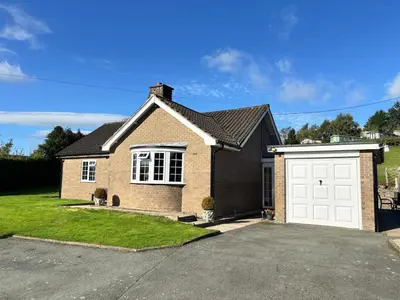 a brown brick house with a white garage at Ty Newydd in Llangyniew