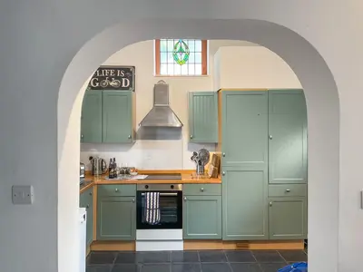 an archway in a kitchen with green cabinets at Archers Cottage in Leominster