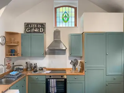 a kitchen with green cabinets and a sink and a window at Archers Cottage in Leominster