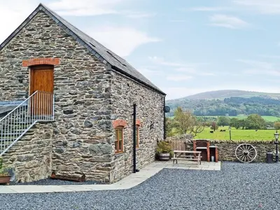 a stone barn with a wooden door and a patio at Granary - Uk50617 in Corwen