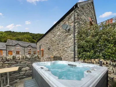 a hot tub in front of a stone building at Granary - Uk50617 in Corwen