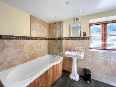 a bathroom with a bath tub and a sink at Granary - Uk50617 in Corwen