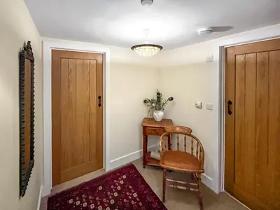 a hallway with a wooden door and a chair and a table at Granary - Uk50617 in Corwen