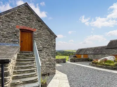 a stone house with a wooden door and stairs at Granary - Uk50617 in Corwen