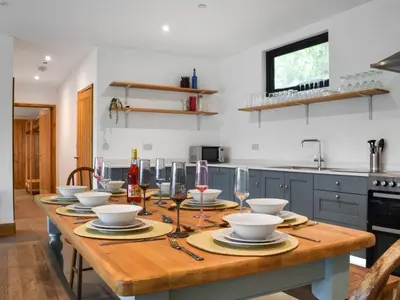 a kitchen with a wooden table with bowls and wine glasses at Acre Luxury Lodges-Cedar Lodge in Evenjobb