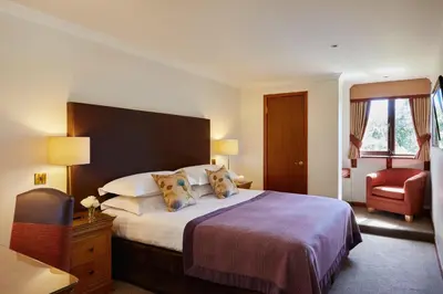 a hotel room with a bed and a chair at Macdonald Plas Talgarth Resort in Aberdyfi