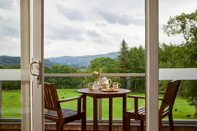 a table and two chairs on a balcony with a window at Macdonald Plas Talgarth Resort in Aberdyfi