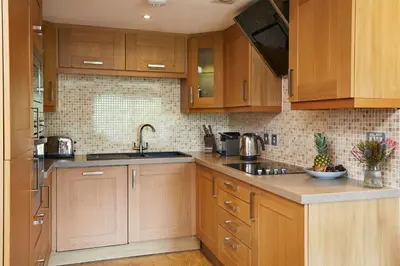 a kitchen with wooden cabinets and a sink at Macdonald Plas Talgarth Resort in Aberdyfi