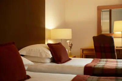 a hotel room with two beds and a mirror at Macdonald Plas Talgarth Resort in Aberdyfi
