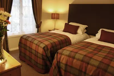 a hotel room with two beds and a window at Macdonald Plas Talgarth Resort in Aberdyfi