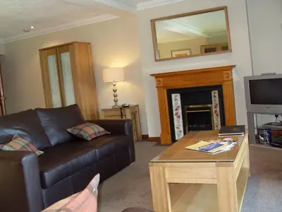 a living room with a leather couch and a fireplace at Macdonald Plas Talgarth Resort in Aberdyfi