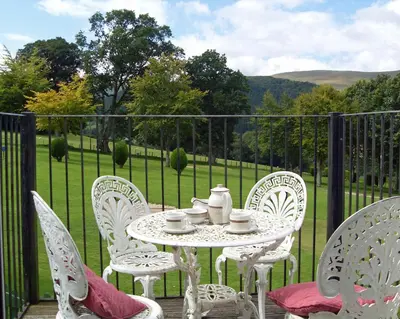 a table and chairs on a patio with a view of a field at Macdonald Plas Talgarth Resort in Aberdyfi