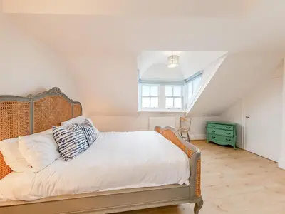 a bedroom with a bed with white sheets and a window at The Penthouse Westhaven in Aberdyfi