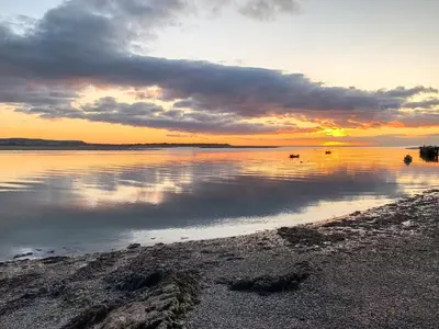 a sunset over a body of water with clouds at The Penthouse Westhaven in Aberdyfi