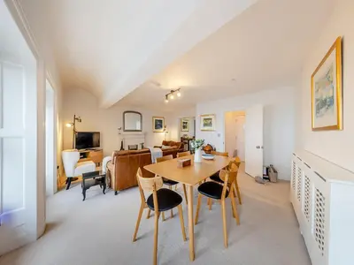 a dining room and living room with a table and chairs at The Penthouse Westhaven in Aberdyfi