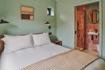 a bedroom with a white bed and a bathroom at Hay Barn in Trefeglwys