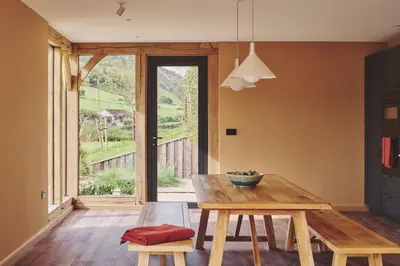 a dining room with a table and benches and a window at Hay Barn in Trefeglwys