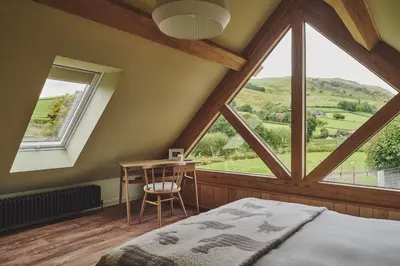 a bedroom with a large window and a desk and a bed at Hay Barn in Trefeglwys