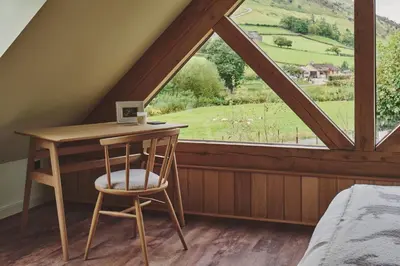 a bedroom with a desk and a large window at Hay Barn in Trefeglwys