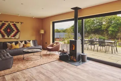a living room with a fireplace and a patio with a table at Hay Barn in Trefeglwys