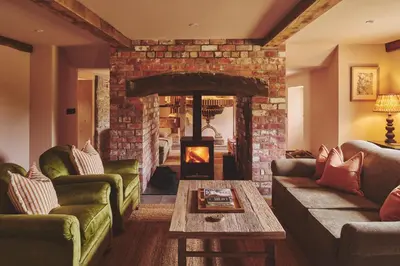 a living room with a fireplace with couches and a table at Mill House in Trefeglwys