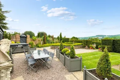 a patio with a table and chairs in a garden at The Topiary by Birch Stays in Wollaston