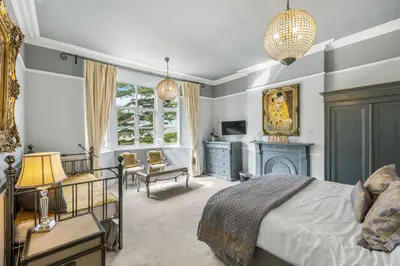 a bedroom with a bed and a chair and a fireplace at The Topiary by Birch Stays in Wollaston