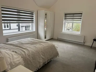 a white bedroom with two windows and a bed at Llangollen - House - Sleeps 8- Garden in Llangollen