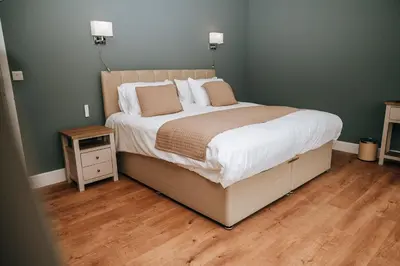a bedroom with a large bed and a wooden floor at Beacons View Luxury Lakeside Chalet- Trem Y Fan in Brecon