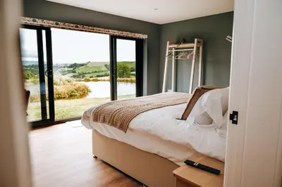 a bedroom with a bed and a large window at Beacons View Luxury Lakeside Chalet- Trem Y Fan in Brecon
