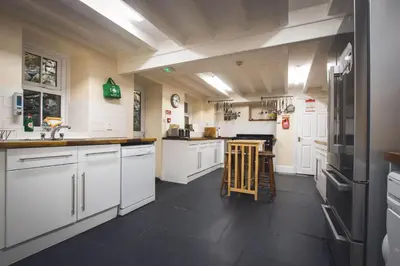 a large kitchen with white cabinets and black appliances at Noddfa Country House in Harlech